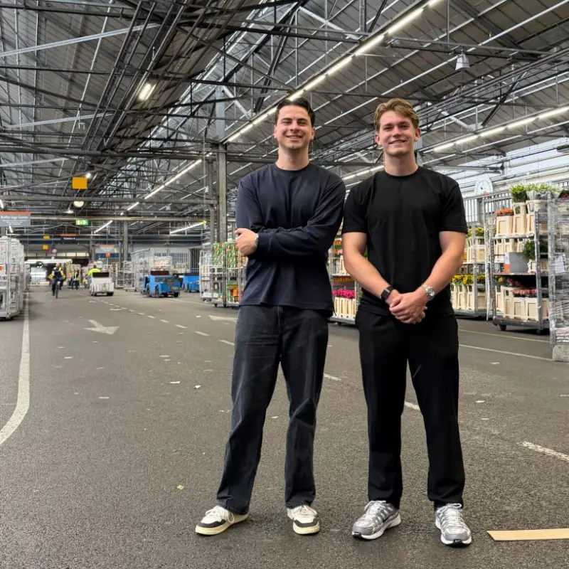 Ties Mol en Sam Andringa in een veilinghal, tussen de karren met planten